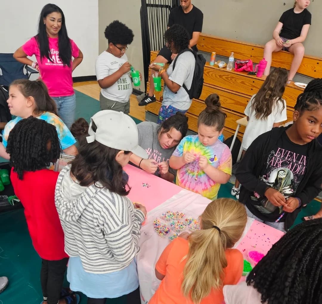 Children crowded along a bead-covered table threading their own bracelets at a C.A.N. event