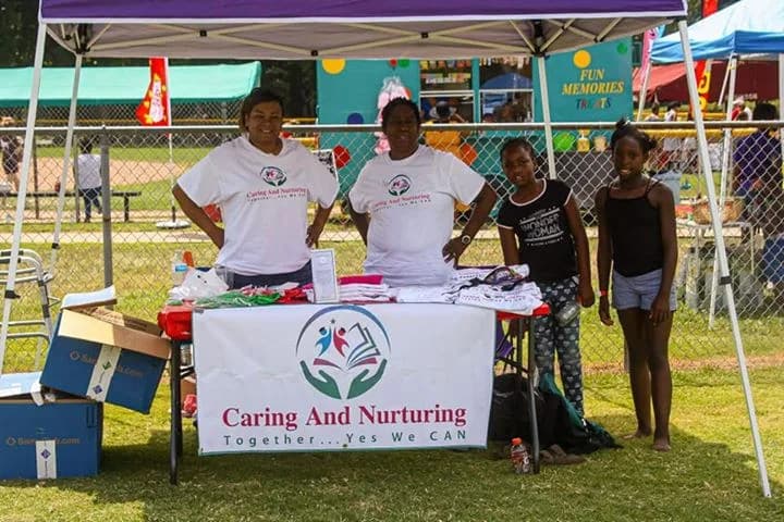 Two C.A.N. volunteers behind the Caring And Nurturing table at a community event