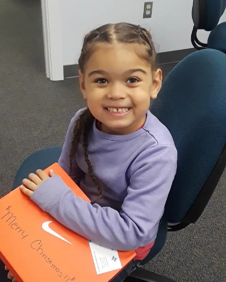 A girl holding the Christmas gift box she received from C.A.N.