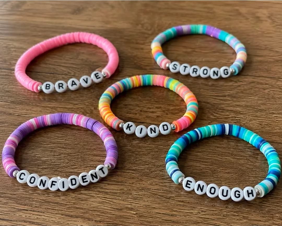 Five handmade bracelets spelling BRAVE, STRONG, KIND, CONFIDENT and ENOUGH in letter beads