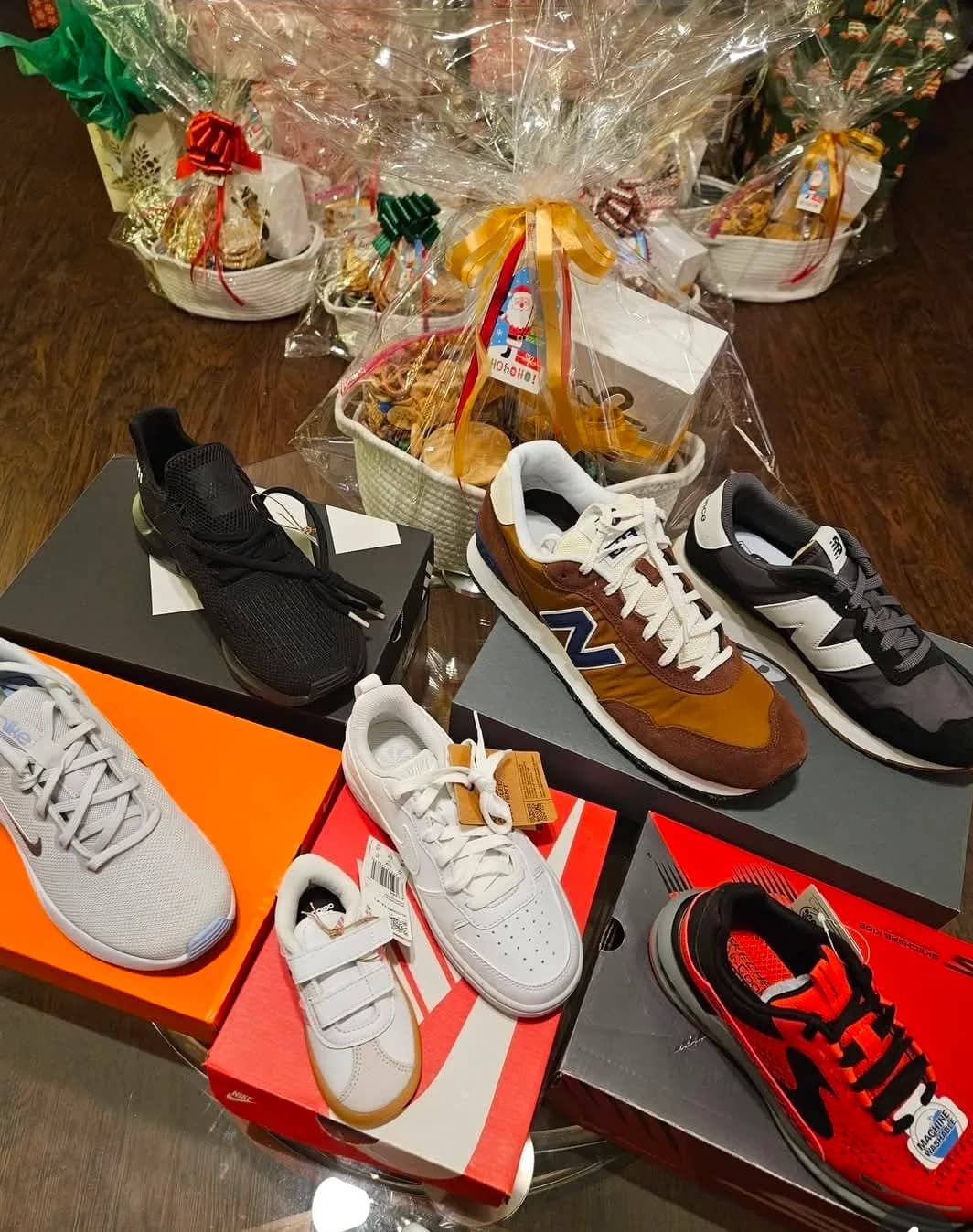 Brand new shoes laid out on their boxes in front of wrapped Christmas baskets