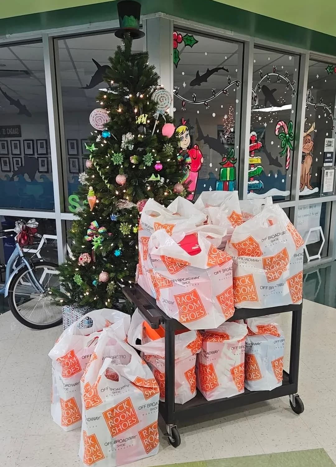 Bags of donated shoes stacked on a trolley beside a decorated Christmas tree